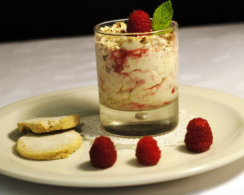 Dessert in a glass with raspberries on a plate