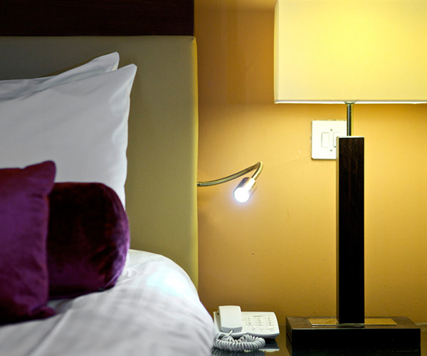 Bed with bedside light at Parliament House Hotel