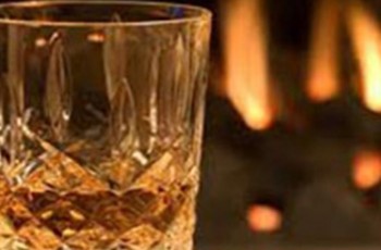 Glass of whisky by and open fire
