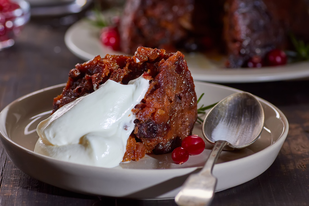 A portion of Christmas Pudding served on a plate with cream