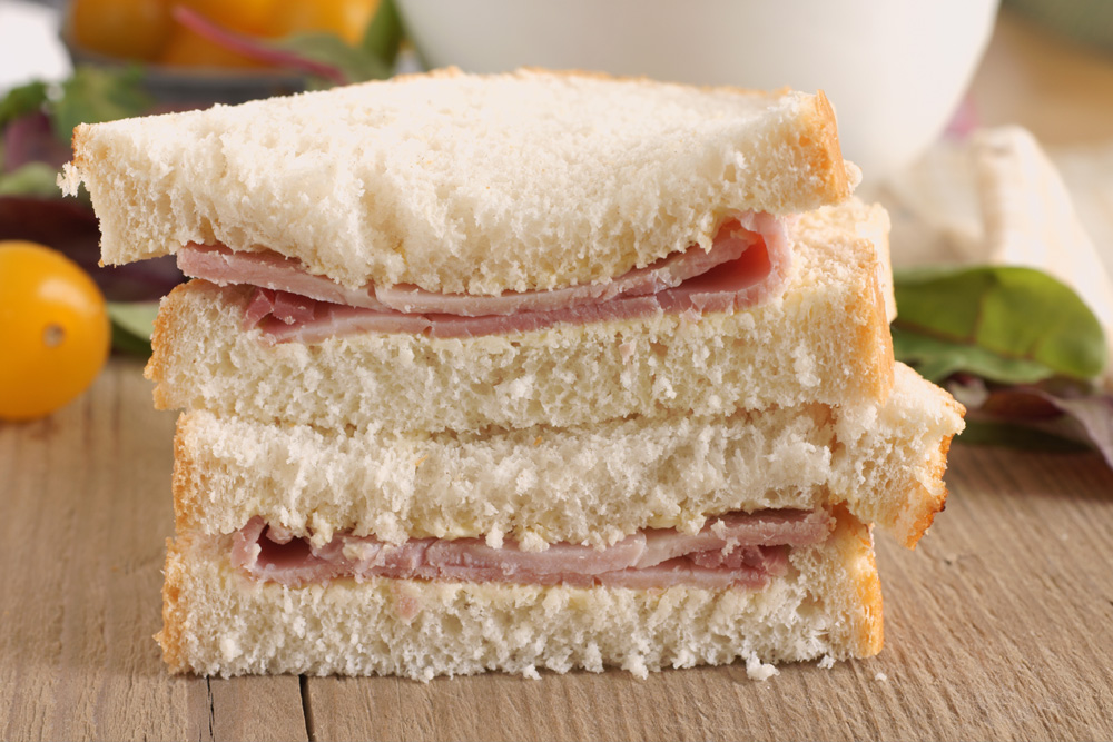 A ham sandwich on white bread and cut in half