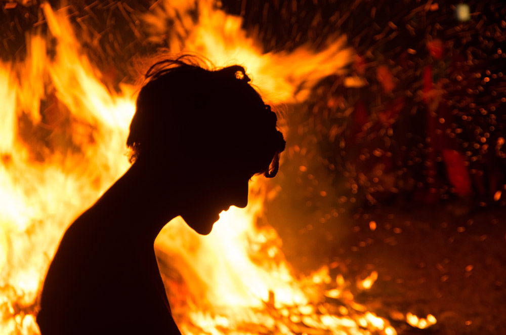 Silhouette of man in front of bonfire