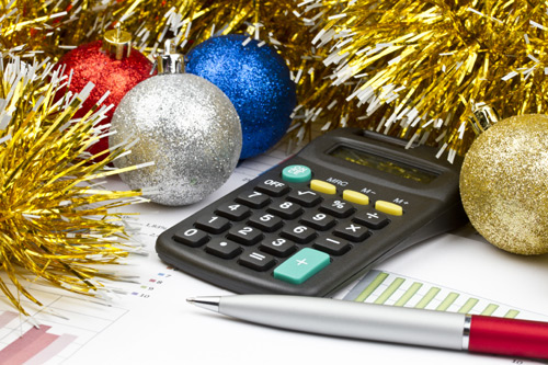 Pen, notebook and calculator surrounded by Christmas baubles and tinsel