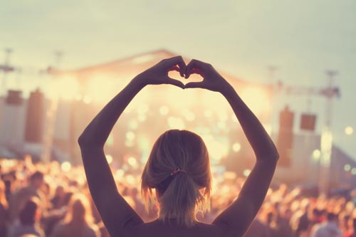 Member of audience at a concert making a heart shape with her hands