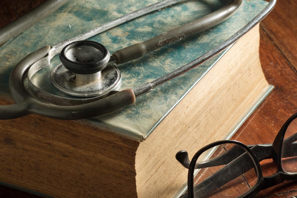 Old medical book, stethoscope and glasses