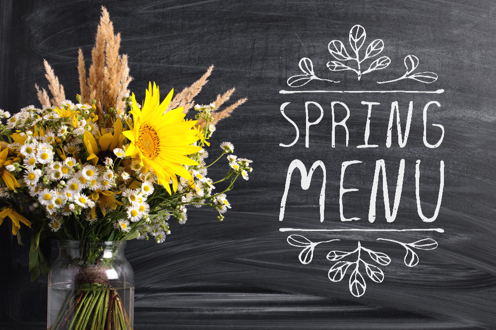 Spring menu on chalk board with flowers in foreground
