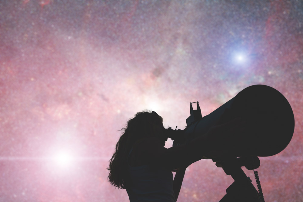 Woman with telescope against night sky