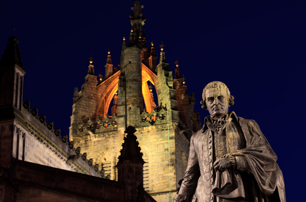 Statue of Adam Smith in Edinburgh with cathedral in background