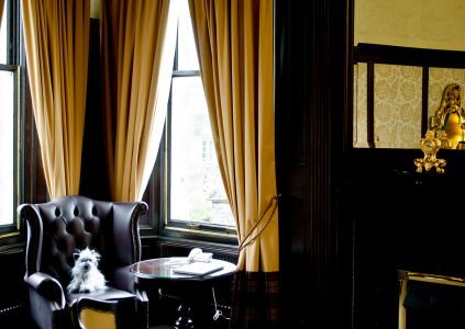 A bay window with a leather wingback armchair in the Suite in Parliament House Hotel in Edinburgh