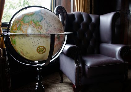 A large globe by a leather wingback armchair in the Suite in Parliament House Hotel in Edinburgh