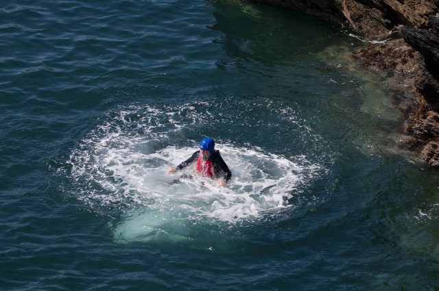 A person who is coasteering and just cliff jumped into the sea