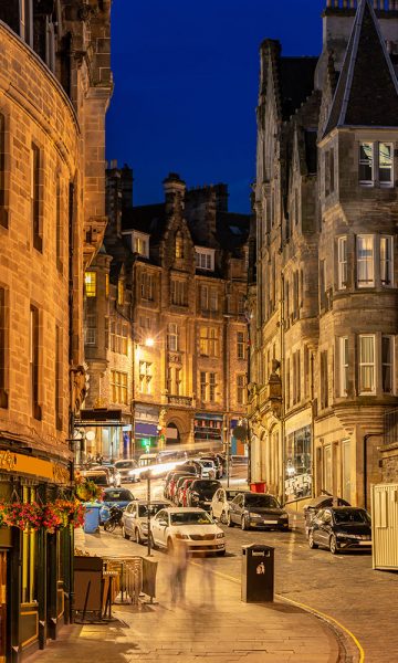 The winding cobbled hill and buildings of Victoria Street in Edinburgh lit up at night