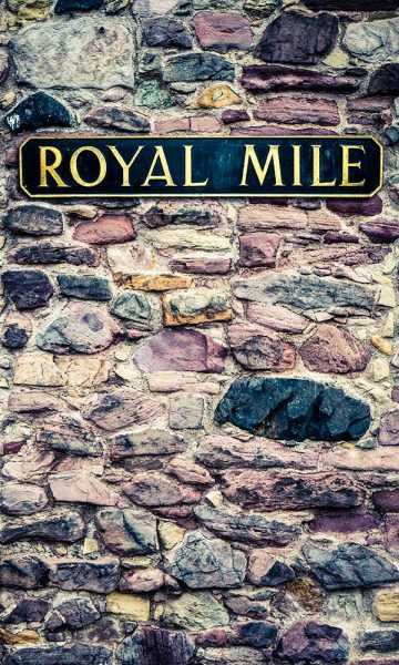 A street sign for the Royal Mile on an old stone wall