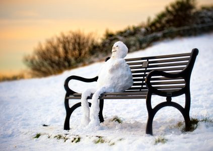 A snowman on a park bench at sunset in Edinburgh