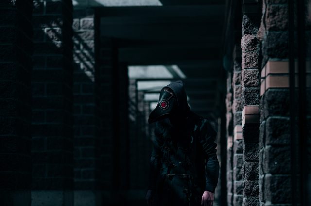 A plague doctor walking a darkened alley