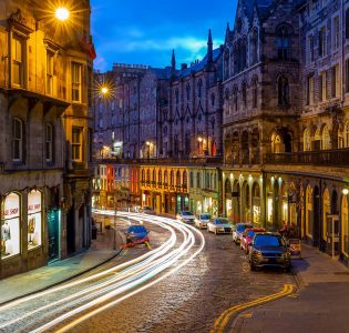 Victoria Street lit up at night with its colourful shop fronts and cobbled hill