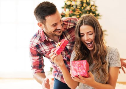 A girl looking delighted when opening her partners Christmas present