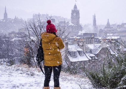 A girl wrapped up and looking over Edinburgh in the snow
