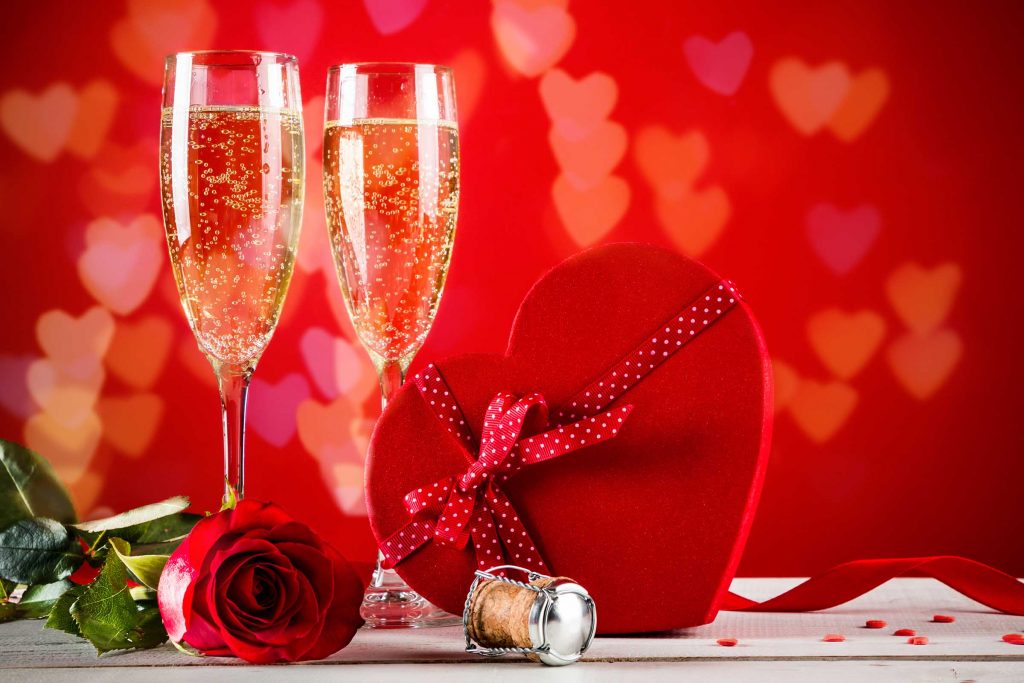 Two glasses of champagne, a red rose and a heart shaped box of chocolates on Valentines day