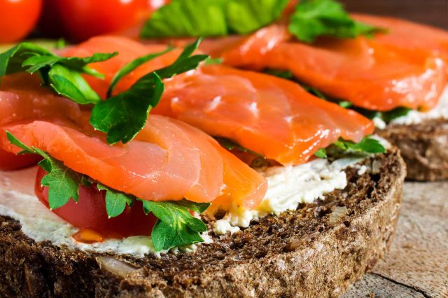 Homemade slices of bread topped with salmon, spreadable cheese and rocket
