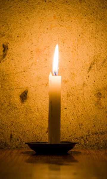 A candle against dark stone wall