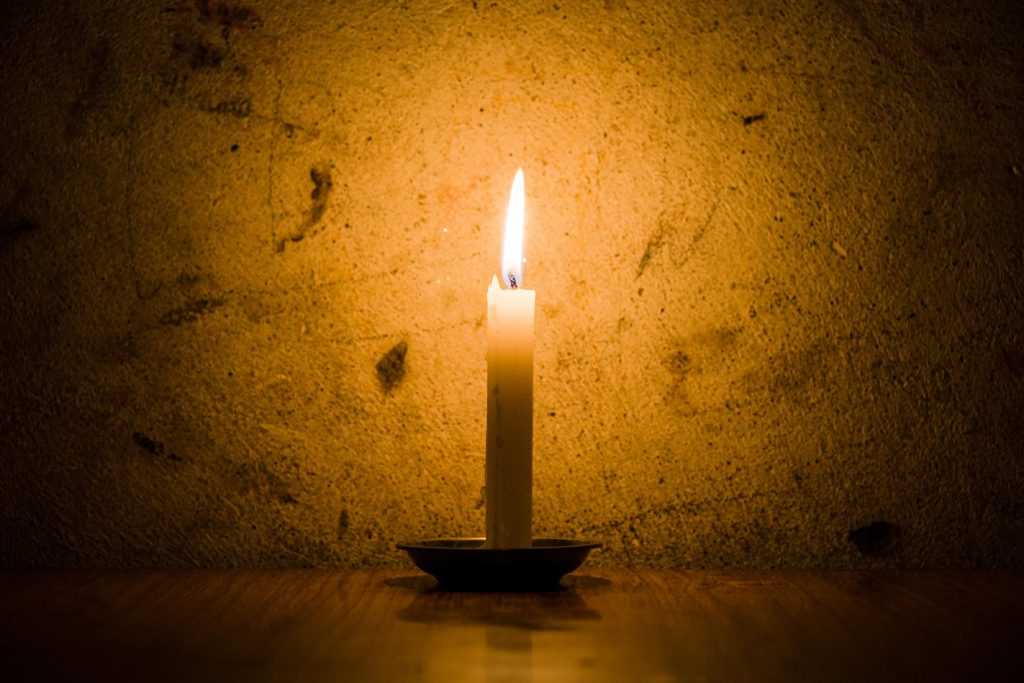 A candle against dark stone wall