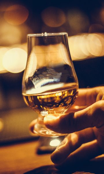 Close up of hand holding a dram of whisky